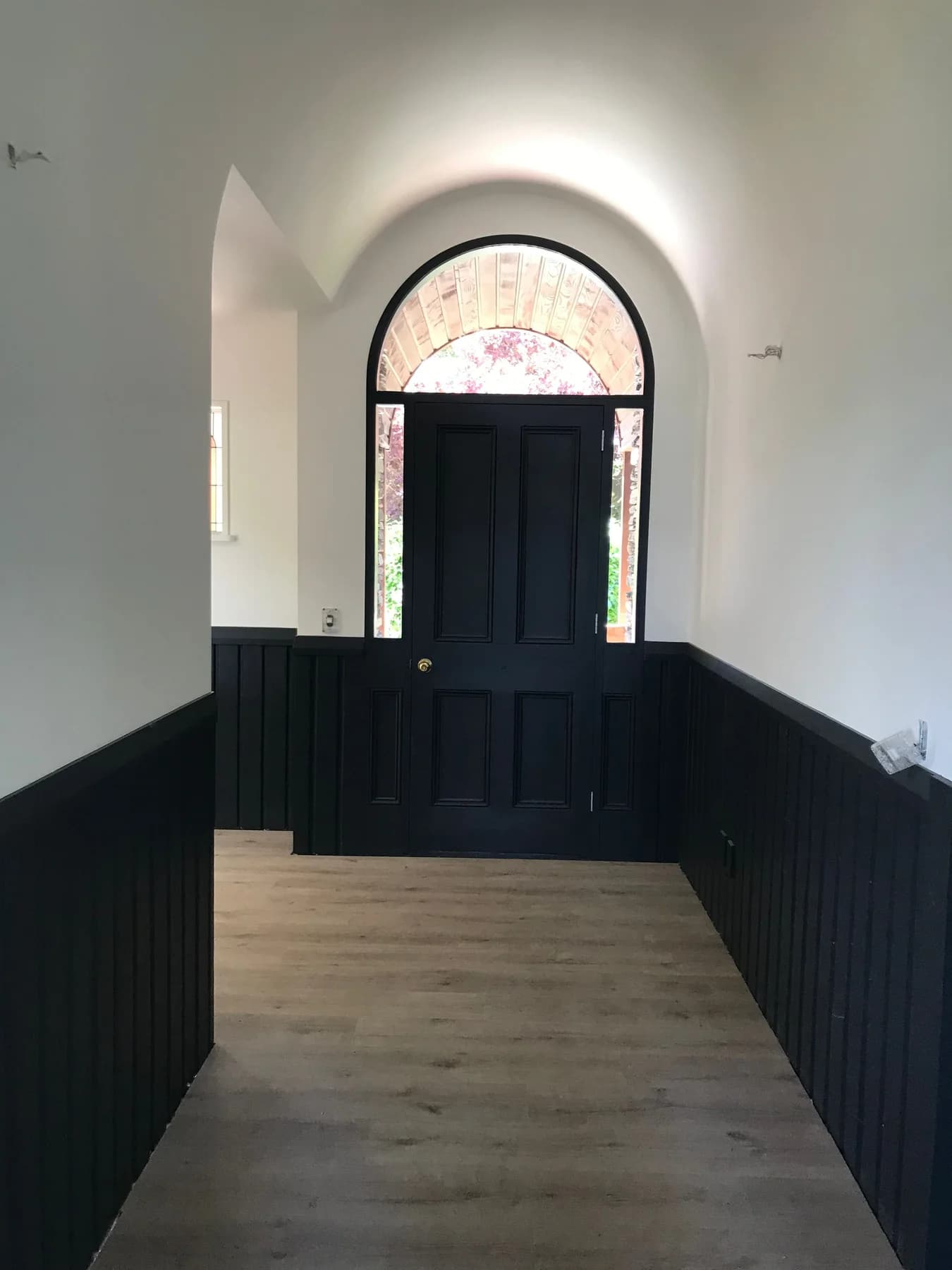 Freshly painted character entry with dark timber panelling and an arched doorway