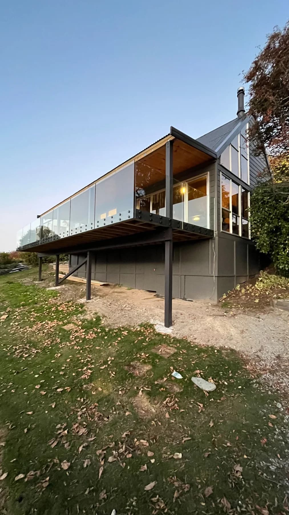 Dark-painted architectural Queenstown home with vertical cladding and a glass balcony at dusk