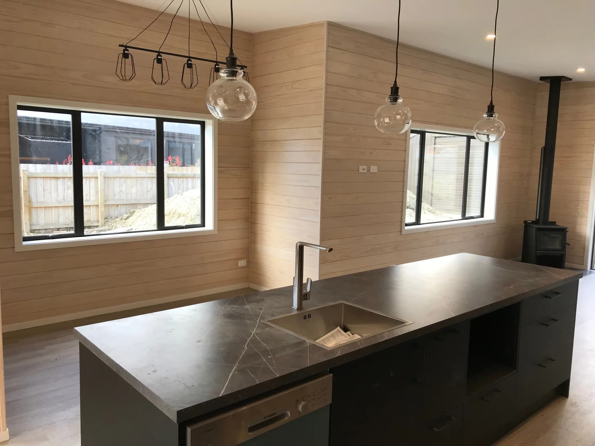 Open-plan kitchen and living area with whitewashed timber ceilings and walls