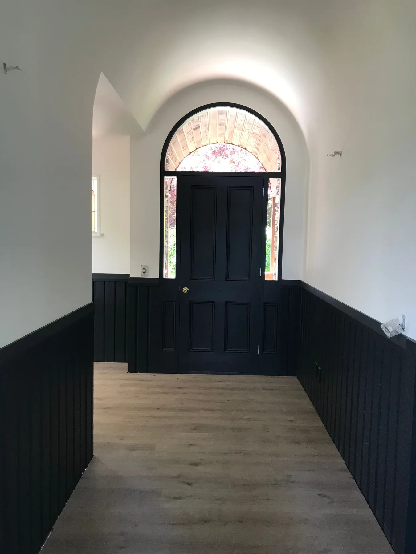 Freshly painted character entry with dark timber panelling and an arched doorway