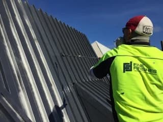 Fine Finishes painter coating a metal roof
