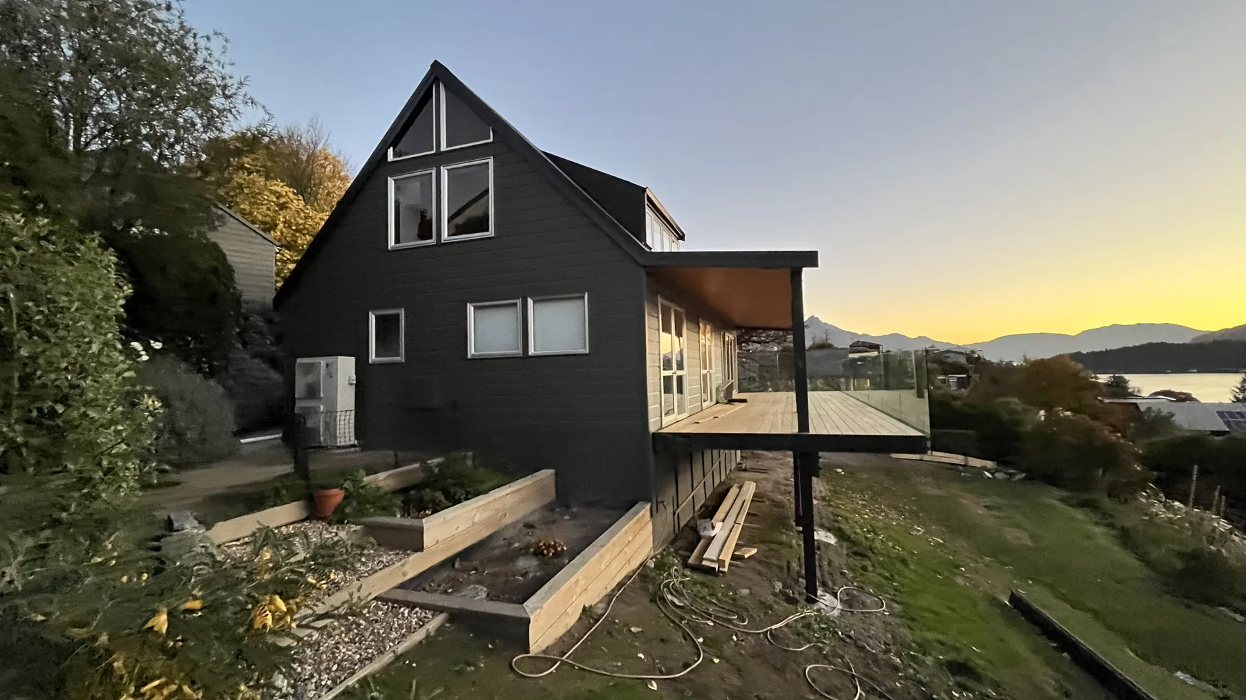 Dark-painted gable home finished by Fine Finishes, with lake and mountains at dusk